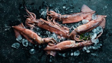 Siyah taşlı arka planda buzdaki mürekkep balığı. Deniz ürünleri. Karanlık bir arka planda.