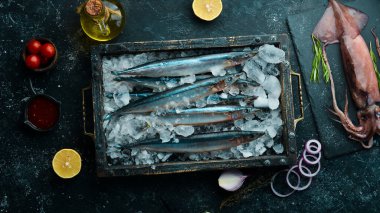 Siyah bir arka planda buzda çiğ balık saira. Deniz ürünleri. Karanlık bir arka planda.