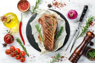 Kemiklerde ızgara New York bifteği, baharatlar ve otlar. Sulu pişmiş biftek. Üst Manzara. Kırsal tarzda. Düz Yat.