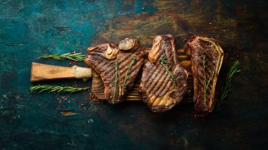 Tahtada ızgara et bifteği: t-bone, striploin, kaburga, New York bifteği. Üst Manzara. Kırsal biçim.