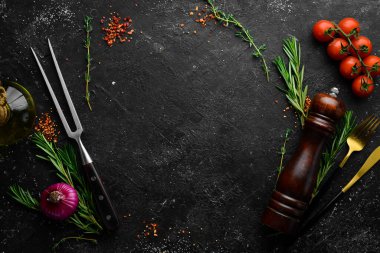 Baharatlar, otlar ve mutfak aletleriyle dolu siyah taş mutfak arka planı. Metin için boş alan. Üst Manzara. Kırsal biçim.