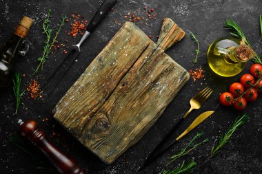 Baharatlar, otlar ve mutfak aletleriyle dolu siyah taş mutfak arka planı. Metin için boş alan. Üst Manzara. Kırsal biçim.