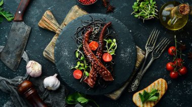 Sarımsak sosunda pişirilmiş ahtapot dokunaçları ve mürekkepbalıklı kara makarna. Lüks restoran yemekleri. Deniz ürünleri. Kırsal tarzda. Düz Yat.