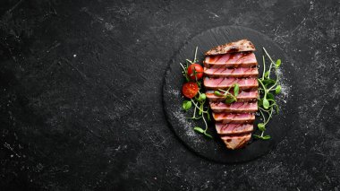 Siyah taş tabakta sebzeli sulu ton balığı bifteği pişirdim. Restoran yemeği. Deniz ürünleri. Kırsal tarzda. Düz Yat.