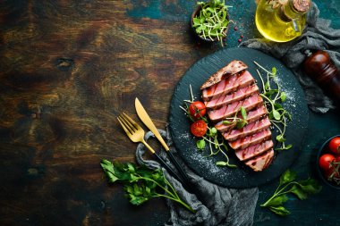 Siyah taş tabakta sebzeli sulu ton balığı bifteği pişirdim. Restoran yemeği. Deniz ürünleri. Kırsal tarzda. Düz Yat.