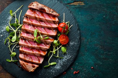 Siyah taş tabakta sebzeli sulu ton balığı bifteği pişirdim. Restoran yemeği. Deniz ürünleri. Kırsal tarzda. Düz Yat.