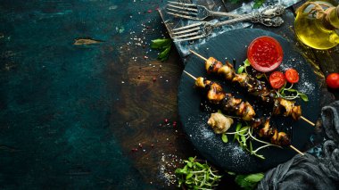 Siyah taştan bir tabakta sebzeli Rapana şişleri. Restoran yemeği. Deniz ürünleri. Kırsal tarzda. Düz Yat.