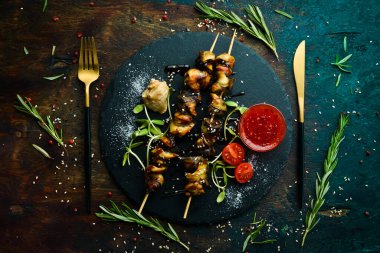Siyah taştan bir tabakta sebzeli Rapana şişleri. Restoran yemeği. Deniz ürünleri. Kırsal tarzda. Düz Yat.