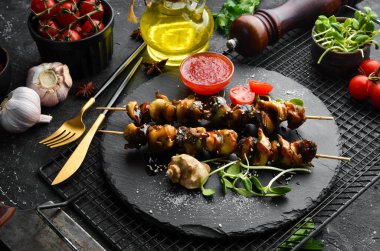 Siyah taştan bir tabakta sebzeli Rapana şişleri. Restoran yemeği. Deniz ürünleri. Kırsal tarzda. Düz Yat.