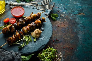 Siyah taştan bir tabakta sebzeli Rapana şişleri. Restoran yemeği. Deniz ürünleri. Kırsal tarzda. Düz Yat.