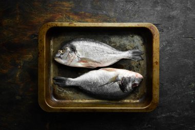 Metal tepside Dorado balığı. Balık pişirme tarifi. Üst Manzara. Bedava fotokopi. Siyah taştan bir arka planda.