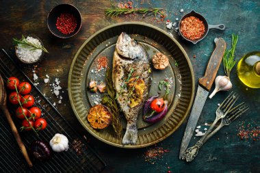 Metal tepside kuşkonmaz ve sebzeli fırında dorado balığı. Bedava fotokopi. Siyah taştan bir arka planda.