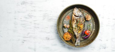 Lezzetli fırında pişirilmiş, otlu ve limonlu balık, metal fırın tepsisinde. Dorado. Beyaz ahşap arka planda.