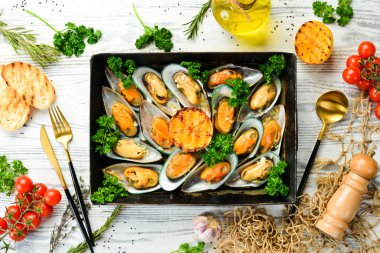 Sarımsaklı, maydanozlu ve limonlu midye pişirdim. Deniz ürünleri. Beyaz ahşap bir arka planda. Metin için boş alan.