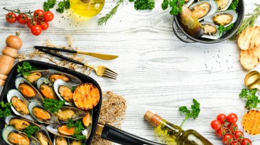 Sarımsaklı, maydanozlu ve limonlu midye pişirdim. Deniz ürünleri. Beyaz ahşap bir arka planda. Metin için boş alan.