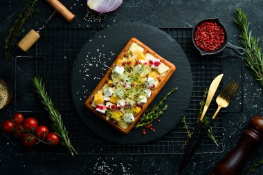 Kahvaltıda. Krem peynirli Belçika waffleları, peynir ve parmesan peyniri. Siyah taştan bir tabakta.
