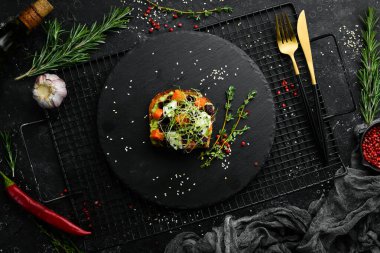 Sandviç: ciabatta, avokado, pancar ve havuç. Kahvaltıda. Siyah taştan bir tabakta.