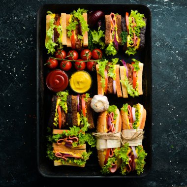 Sosis, pirzola, marul, soğan, domates ve sebzeli ev yapımı sandviçler. Kırsal tarzda. Boş kopyalama alanı.