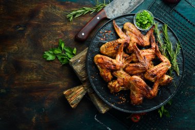 Siyah taş tabakta soslu ve baharatlı ızgara tavuk kanadı. Üst Manzara. Metin için boş alan.