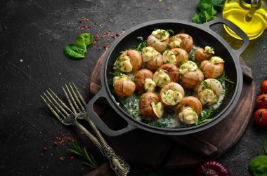 Sarımsaklı Bourgogne Salyangoz, siyah taş tabakta krem soslu peynir. Üst Manzara. Metin için boş alan.