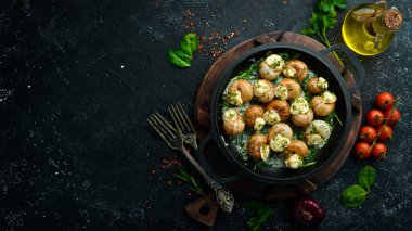 Sarımsaklı Bourgogne Salyangoz, siyah taş tabakta krem soslu peynir. Üst Manzara. Metin için boş alan.
