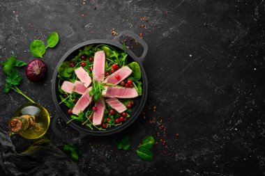 Salata: roka, ton balığı ve siyah taş tabakta avokado. Üst Manzara. Metin için boş alan.