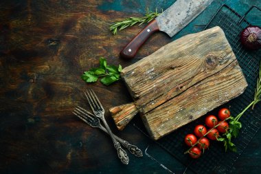 Mutfak tahtası, sebzeler, baharatlar ve otlar siyah taştan bir arka planda. Mutfak arka planı. Üst Manzara. Metin için boş alan.