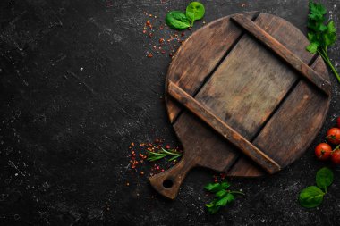 Mutfak tahtası, sebzeler, baharatlar ve otlar siyah taştan bir arka planda. Mutfak arka planı. Üst Manzara. Metin için boş alan.