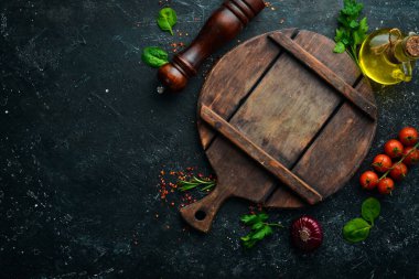 Mutfak tahtası, sebzeler, baharatlar ve otlar siyah taştan bir arka planda. Mutfak arka planı. Üst Manzara. Metin için boş alan.