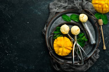 Naneli ve taze mangolu mango dondurması. Dondurma kaşığı. Siyah taştan bir arkaplanda, üst görünüm.