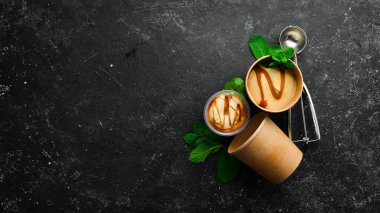 Naneli ve tuzlu karamelli karamelli dondurma. Dondurma kaşığı. Siyah taştan bir arkaplanda, üst görünüm.