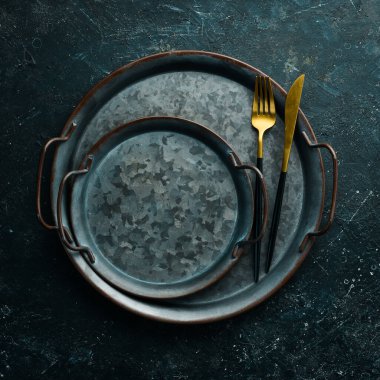 Klasik çatal bıçak takımı ve metal plaka. Siyah taştan bir arkaplanda, üst görünüm.