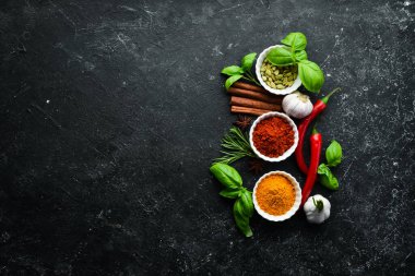 Siyah taştan bir arka planda Hint baharatları ve otları. Üst Manzara. Metin için boş alan.