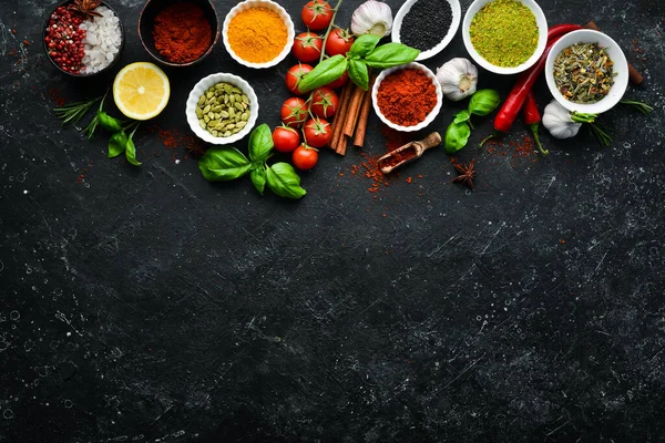 Set of Indian fragrant spices and herbs on a black stone background. Top view. Free space for text.