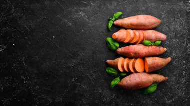 Siyah bir arka planda çiğ patates ve fesleğen. Üst Manzara. Metnin için boş yer.