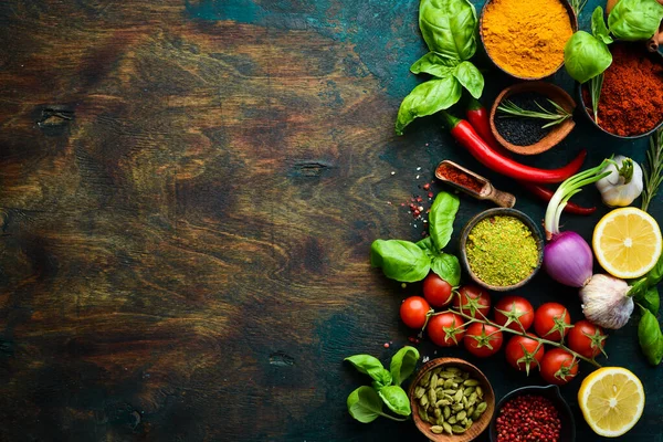 Fragrant spices, herbs and basil on a dark wooden background. Top view. Free space for text.