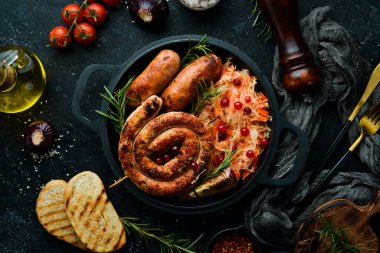 Siyah tabakta lahana turşusu ve ızgara sosis, biberiye ve kızılcık. Geleneksel Alman yemeği. Üst Manzara. Siyah taştan bir arka planda.
