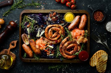 Sosis, fırında lahana, lahana turşusu, baharat ve sebze. Yiyecekler. Üst Manzara. Siyah taştan bir arka planda.