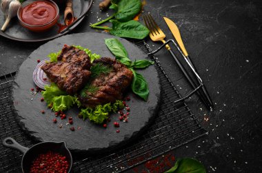 Siyah taş tabakta baharatlı kızarmış domuz bifteği. Üst Manzara. Boş kopyalama alanı.