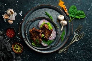 Siyah taş tabakta baharatlı kızarmış domuz bifteği. Üst Manzara. Boş kopyalama alanı.