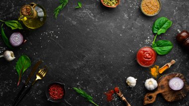 Siyah taş pişirme arka planı. Baharat ve sebze. Üst Manzara. Metnin için boş yer.
