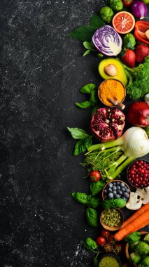 Taze sebze ve meyve: rezene, avokado, nar, böğürtlen, lahana ve fesleğen. Organik sağlıklı vejetaryen yemekleri. Siyah taştan bir arka planda.