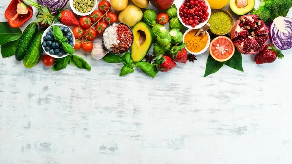 Vegan food banner. Fresh vegetables and fruits and berries on a white wooden background. Free space for your text.