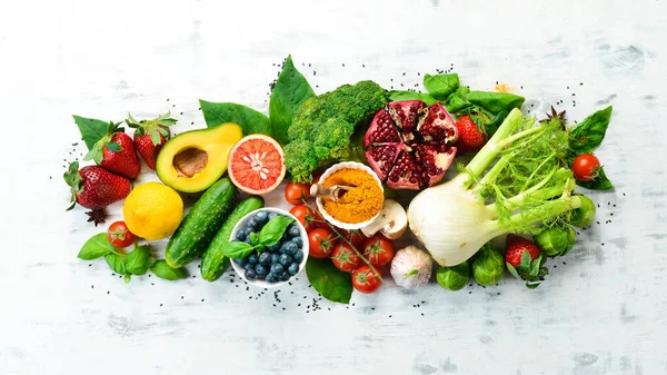 Vegan food banner. Fresh vegetables and fruits and berries on a white wooden background. Free space for your text.