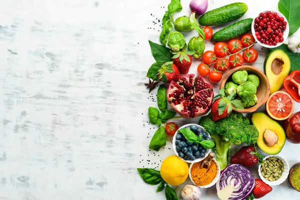 Vegan food banner. Fresh vegetables and fruits and berries on a white wooden background. Free space for your text.