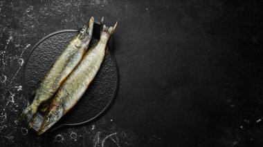 Siyah taş tabakta baharatlı iki balık turna balığı. Karanlık bir arka planda. Üst görünüm.