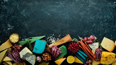 Renkli peynir, sosis, salam ve atıştırmalık. Karanlık bir arka planda. Bedava fotokopi. Üst görünüm.