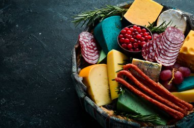 Renkli peynir, sosis, salam ve atıştırmalık. Karanlık bir arka planda. Bedava fotokopi. Üst görünüm.