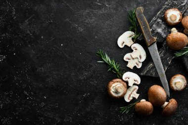 Siyah taşlı arka planda taze şampiyon mantarları. Kırsal tarzda. Üst görünüm.