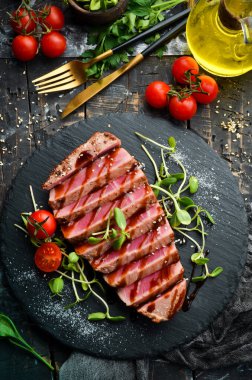 Siyah taş tabakta sebzeli sulu ton balığı bifteği pişirdim. Restoran yemeği. Deniz ürünleri. Kırsal tarzda. Düz Yat.